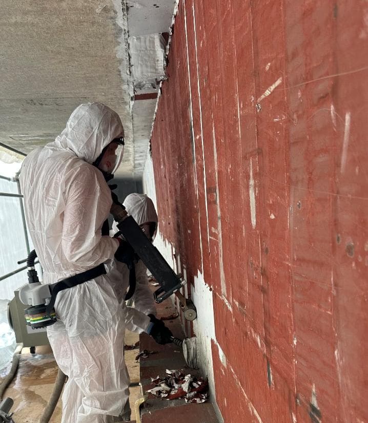 Operatives in protective suits removing paint with an RPR induction tool