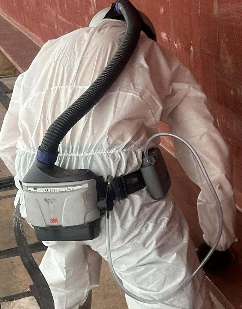 Operative wearing a powered air-purifying respirator and personal air sampler