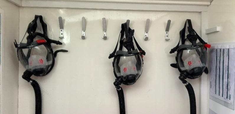 Full-face respirator masks hanging in the clean end of the decontamination unit