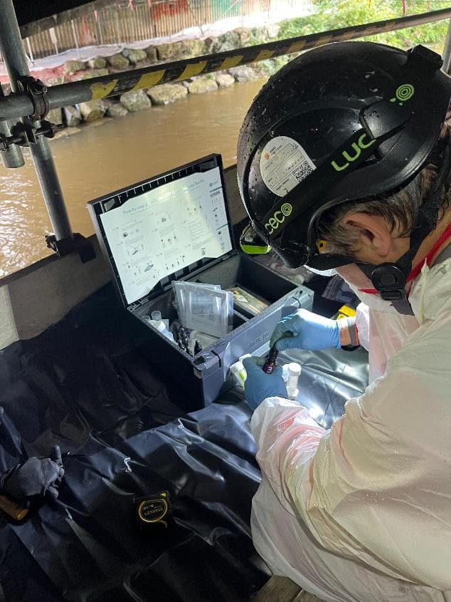 Technician testing a swab sample with a mobile Cr(VI) test kit beside the river