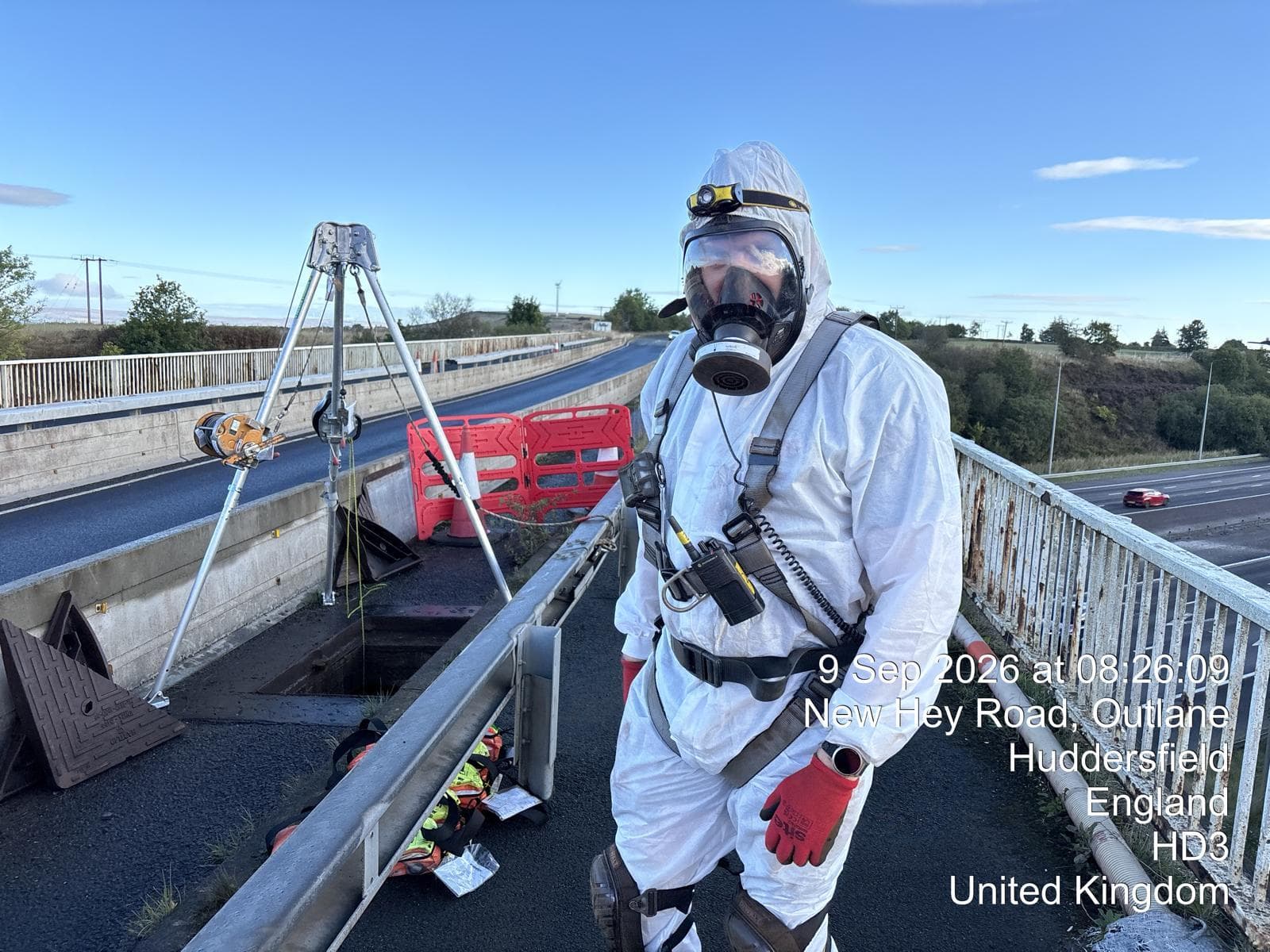 Operative in a powered respirator and harness at the box girder access hatch above the M62, with a rescue tripod set up